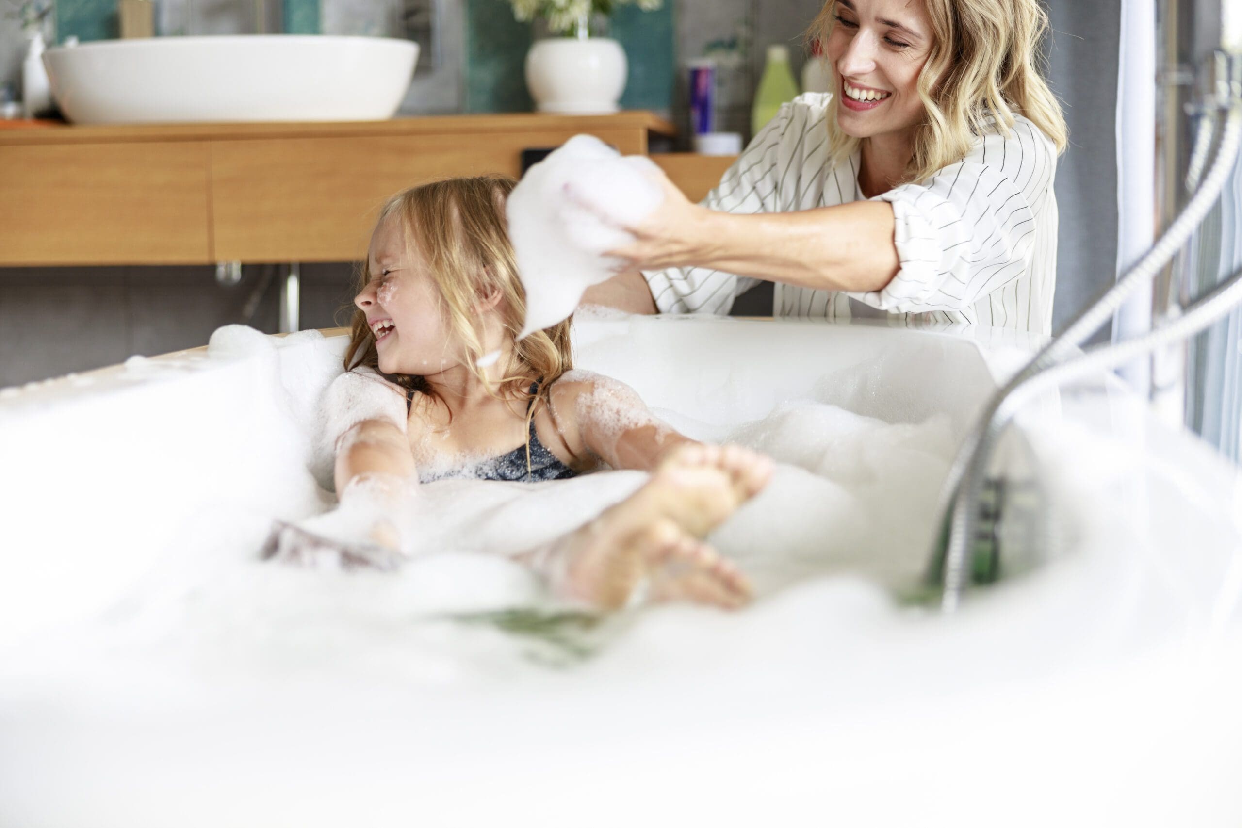 una niña feliz con su madre. Tiene espuma en las manos