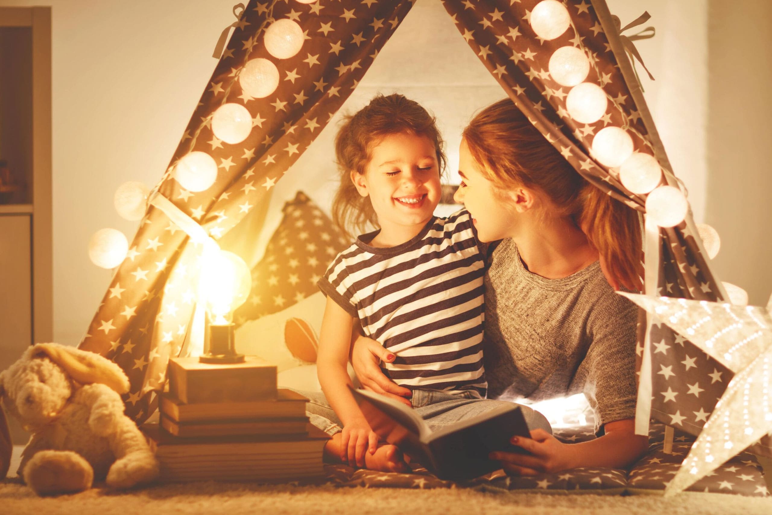 un padre y su hijo feliz leyendo un libro. Al fondo, unas luces decorativas