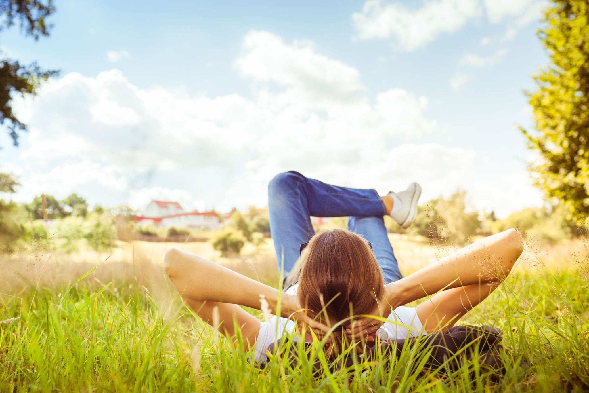 Una mujer relajada en la naturaleza. Está tumbada en el suelo, rodeada de árboles y hierba.