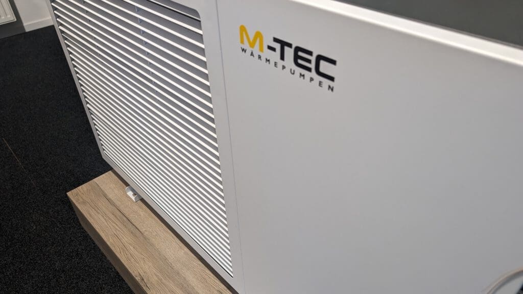 Un dispositivo blanco sobre un trozo de madera. El dispositivo es de color blanco con el logotipo de M-TEC en la parte superior.